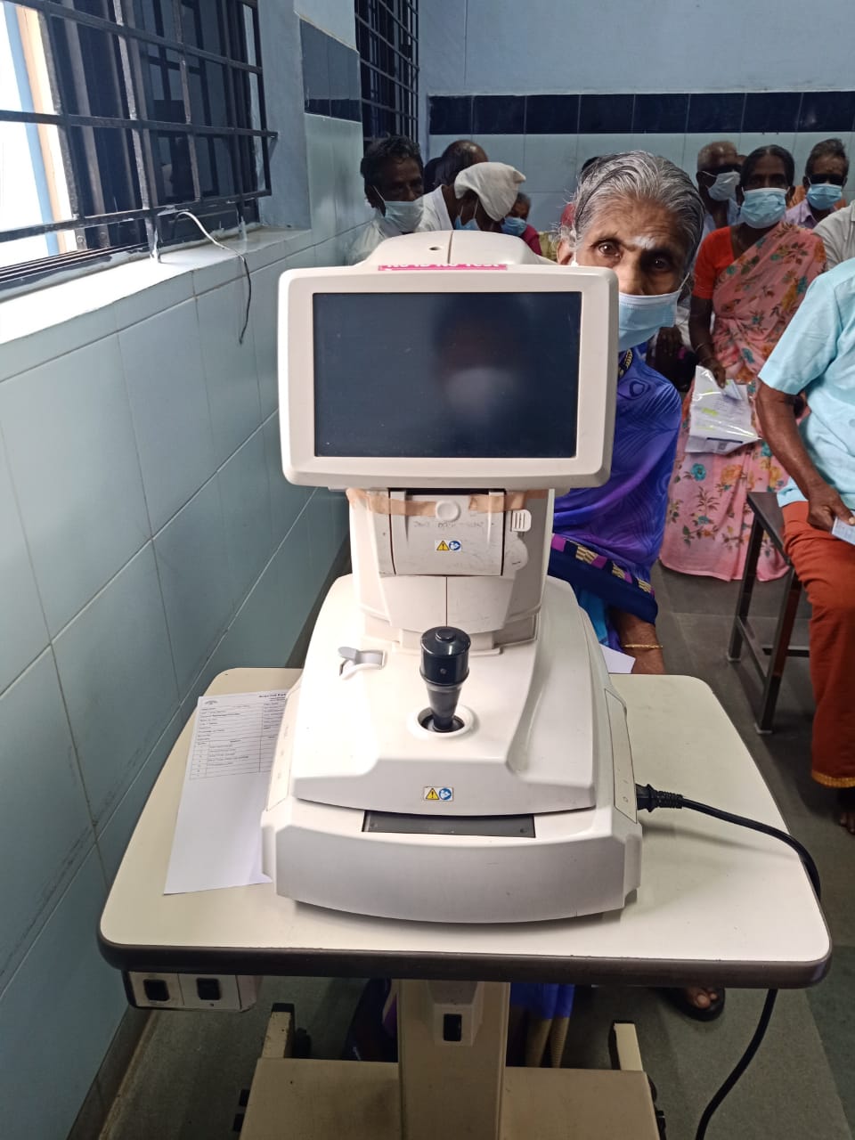 Digital image depicting a patient sitting on an auto-refractor for examination